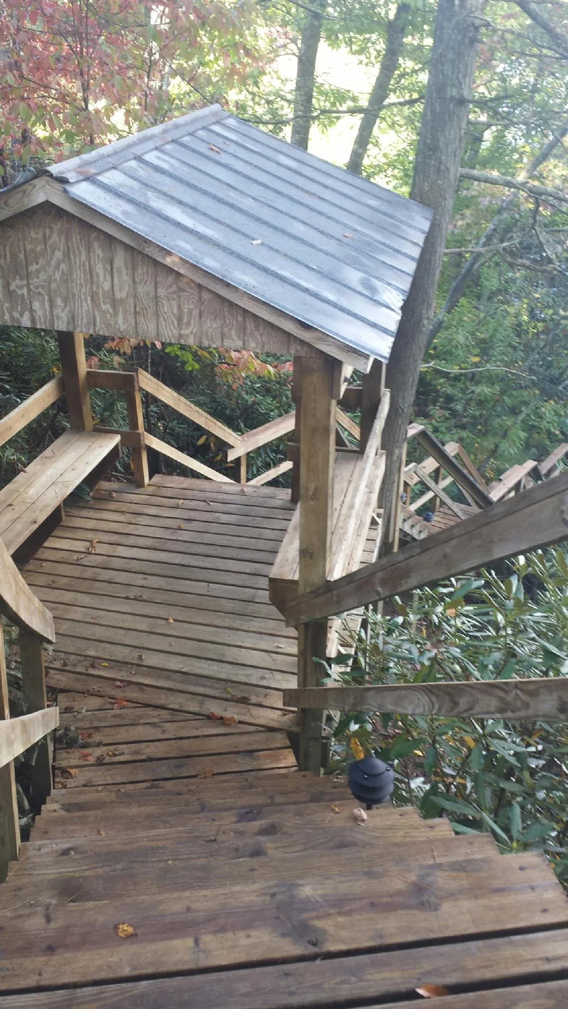 Metal roofed shelter over wooden steps on a wooded walkway — Skylight Repair & Installation work by our crew in Pittsfield